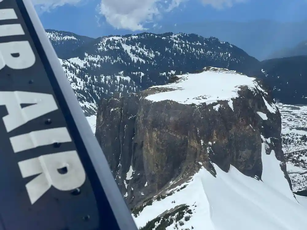 A cliff wall dropping to the lake, seen from the wing