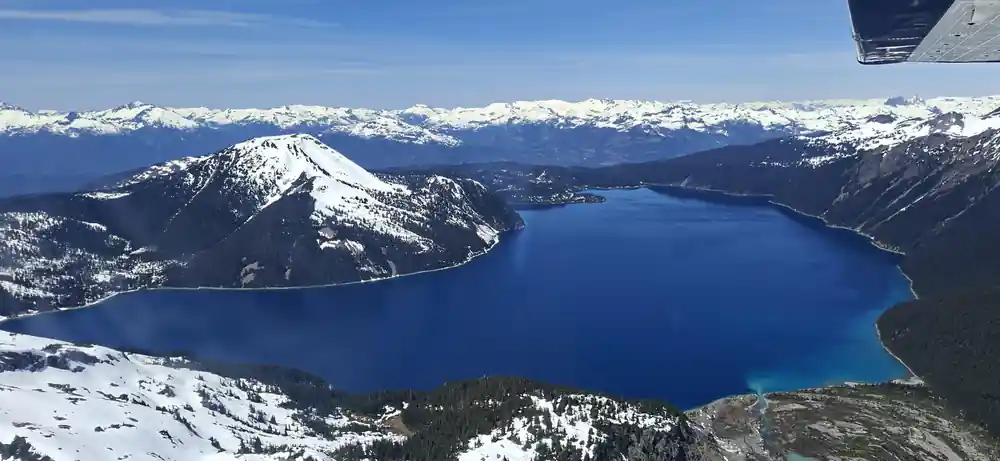 Deep blue lake water below a snow-streaked ridge