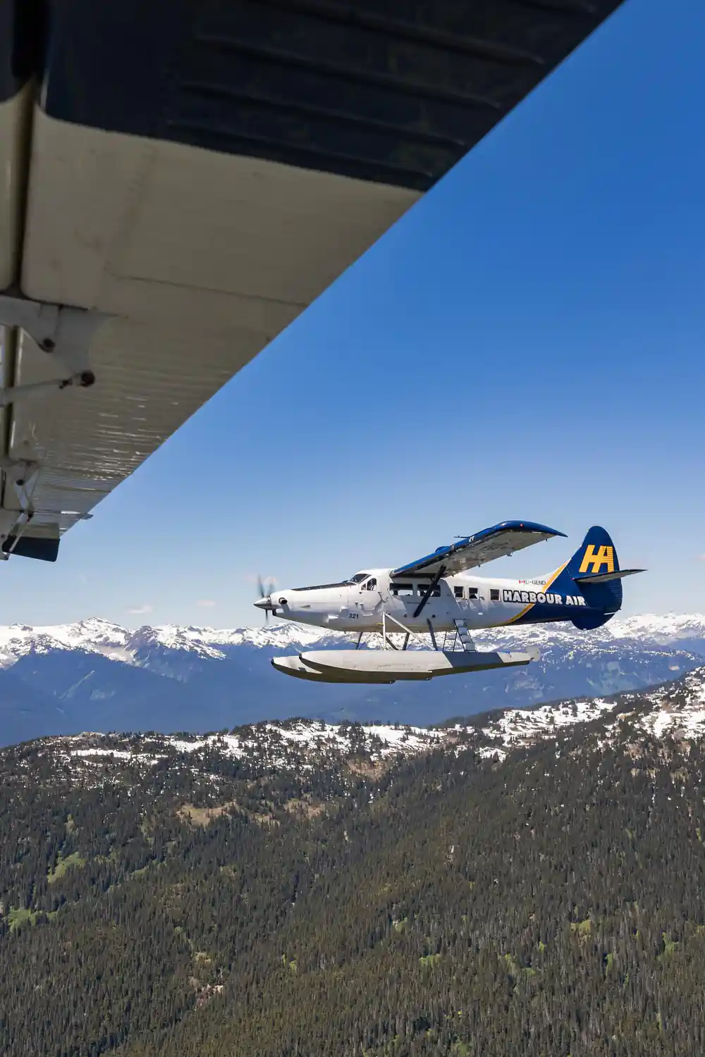 A Harbour Air floatplane in flight above the mountains