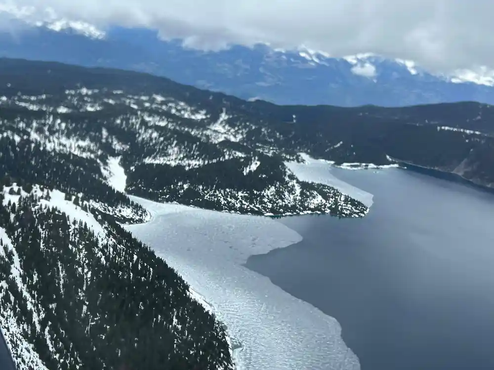 Ice still lying on the lake below a wooded ridge