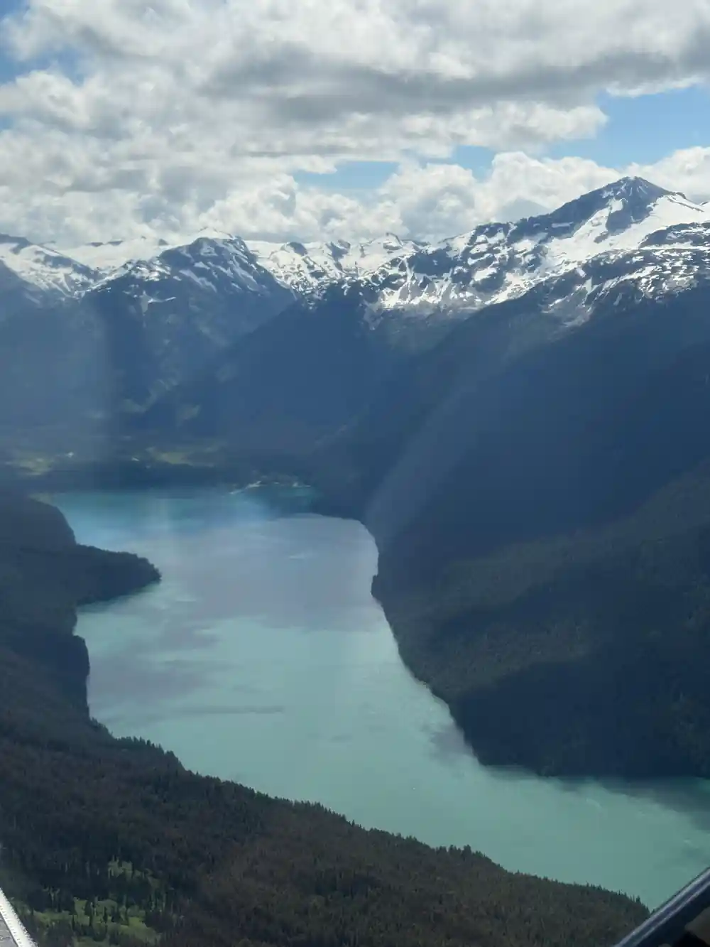A lake filling a valley below snow-topped peaks