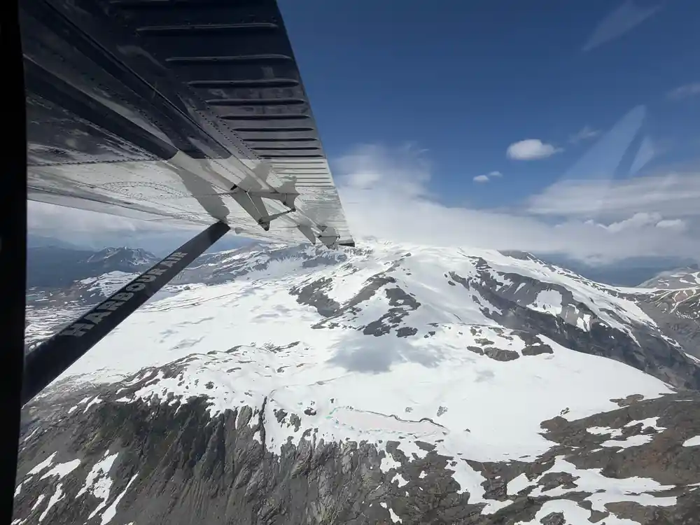 Snow-streaked mountains seen past the wing